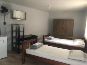 Zimmer mit 2 Betten und einem Schreibtisch mit Ventilator in der Unterkunft Family Hostel in São Paulo