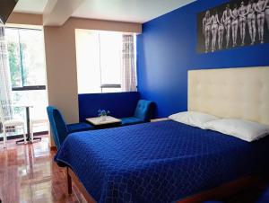 een blauwe slaapkamer met een bed en twee blauwe stoelen bij Munay Wasi CUSCO in Cuzco
