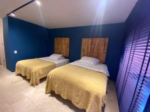 2 Betten in einem Zimmer mit blauen Wänden in der Unterkunft MS Espectacular Suite Terraza Cantalagua in Juriquilla