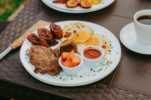 a plate of breakfast food with eggs sausage and fruit at Conceptos Campestre in Huehuetenango