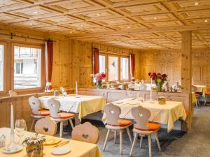 una sala da pranzo con tavoli, sedie e pareti in legno di Alpenhof a Davos