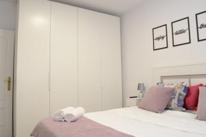 マドリードにあるBonito Apartamento Madrid Rioの白いベッドルーム(紫色の枕が付いたベッド付)