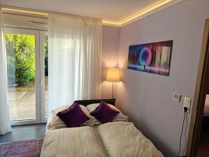 1 dormitorio con 1 cama con almohadas moradas junto a una ventana en Charming apartment with Garden, Free Parking near Basel, Airport, Ger'many, France, en Saint-Louis