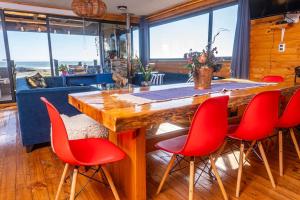 PEZ HOUSE في بتشيلمو: غرفة معيشة مع طاولة خشبية كبيرة وكراسي حمراء