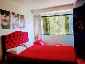 un letto rosso in una camera da letto con finestra di Munay Wasi CUSCO a Cuzco