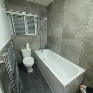 a bathroom with a tub and a toilet and a bath tub at Beautiful place near Dagenham East Station in Dagenham