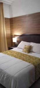 a bedroom with a large white bed with a wooden headboard at Hotel Eduards Suite in Macuto