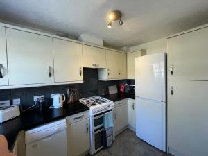 eine Küche mit weißen Schränken und einem weißen Kühlschrank in der Unterkunft Quiet 3 bed home in Stafford