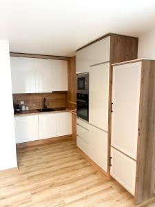 a kitchen with white cabinets and a wooden floor at Studio magnifique avec terrasse spacieuse et jardin Loèche-les-Bains Vacances in Leukerbad