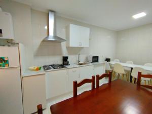 a kitchen with white cabinets and a table and a refrigerator at Marsán in Arzúa