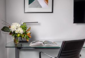 a glass table with a vase of flowers and a book at Rydges Auckland in Auckland