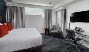 a hotel room with a bed and a desk and a television at Rydges Auckland in Auckland