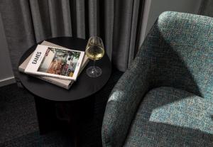 a glass of wine on a table next to a chair at Rydges Auckland in Auckland
