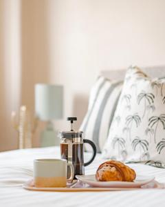 een tafel met een kopje koffie en een gebakje op een bed bij Charming LDN apt with free parking in Londen