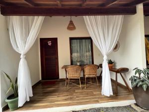 Habitación con cortinas blancas, mesa y sillas. en Pousada e Restaurante Sumaúma en Santarém