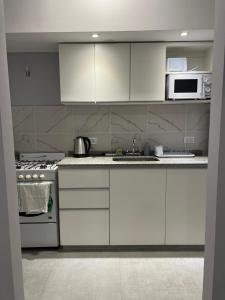 a kitchen with white cabinets and a stove and microwave at Departamentos Oliver in Santa Rosa +5 photos