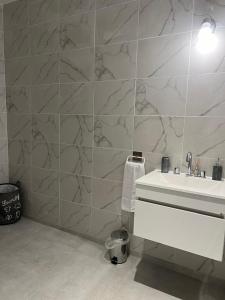a bathroom with a white sink and a marble wall at Departamentos Oliver in Santa Rosa