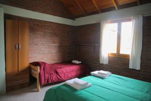 a bedroom with two twin beds and a brick wall at Chacra confluenza in Lago Puelo