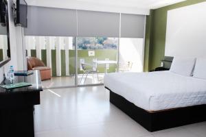 a bedroom with a bed and a balcony with a table at Hotel Borda Cuernavaca in Cuernavaca
