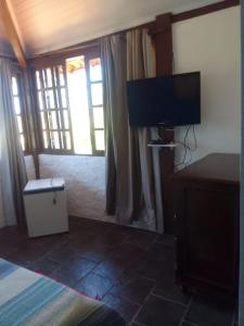 een slaapkamer met een bed en een flatscreen-tv bij Pousada Tupi Imbassai in Imbassai