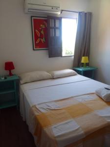 two beds in a room with a window and two lamps at Pousada Tupi Imbassai in Imbassai
