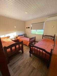 1 dormitorio con 2 camas y ventana en El Lirio en Artigas