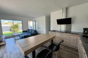 a kitchen and living room with a wooden table and chairs at Splendid new house in Ouistreham in Ouistreham