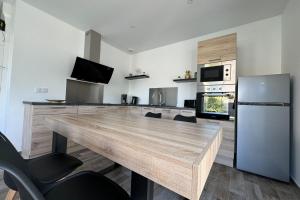 een keuken met een grote houten tafel en een koelkast bij Splendid new house in Ouistreham in Ouistreham