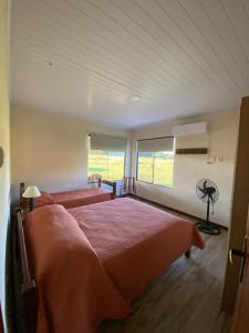 1 dormitorio con 1 cama grande y 2 ventanas en El Lirio en Artigas