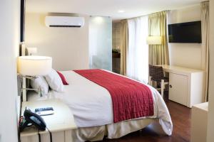 a hotel room with a bed and a desk with a phone at Isabella Boutique Hotel in San Pedro Sula