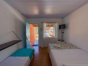 a bedroom with two beds and a tv in it at Pousada Tupi Imbassai in Imbassai