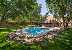 a thatch roofed house with a pool and a yard at Nofa Riyadh, A Radisson Collection Resort in Ţibrāk
