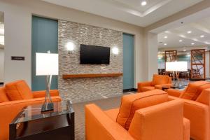 uma sala de espera com cadeiras laranja e uma televisão de ecrã plano em Drury Inn & Suites Charlotte Arrowood em Charlotte