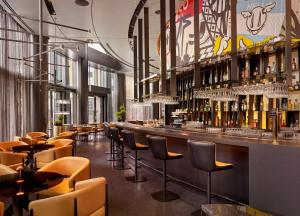 a bar in a restaurant with chairs and wine bottles at art'otel London Hoxton in London