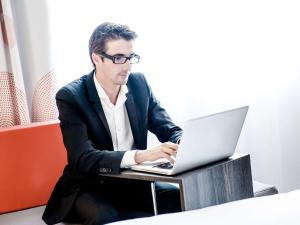 a man sitting at a table with a laptop computer at Novotel Singapore on Kitchener in Singapore