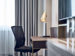 a desk with a chair and a lamp on it at Novotel Singapore on Kitchener in Singapore