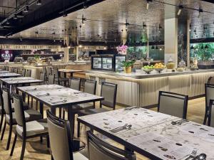 um restaurante com mesas e cadeiras e um bar em Novotel Singapore on Kitchener em Singapura