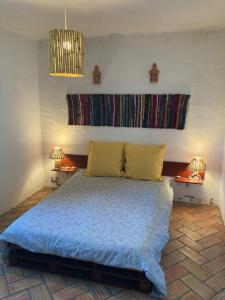 um quarto com uma cama com um cobertor azul e 2 candeeiros em Monte das Flores 