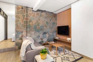 a living room with a couch and a stone wall at MS Luminosa Suite Arcos Hercules HD2 in Laborcillas