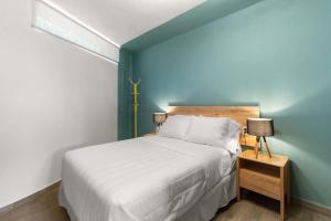 a bedroom with a white bed and a blue wall at MS Luminosa Suite Arcos Hercules HD2 in Laborcillas