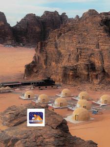 a group of buildings in the desert near a mountain at Nael Bedouin camp in Wadi Rum