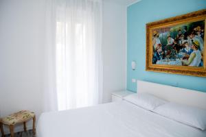a bedroom with a white bed and a painting on the wall at DiBa House 46 in San Vito Chietino +20 photos