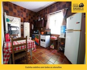 a kitchen with a table and a white refrigerator at Casa Amarela Blumenau Hospedagem Alternativa in Blumenau