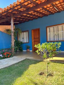 een blauw huis met een boom in de tuin bij Pousada Recanto Rainha do Lago in Capitólio
