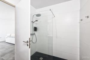een douche in een witte badkamer met een glazen deur bij La Grama I comodidad y excelente ubicación in Breña Alta