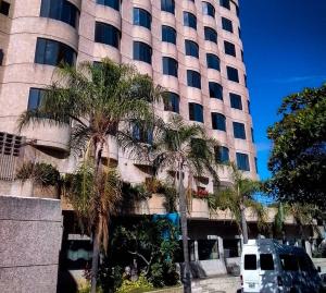 um edifício alto com palmeiras em frente em Hotel Eduards Suite em Macuto
