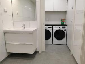 a white kitchen with a washing machine and a sink at Svolvær Apartment, Vestermyrveien 11 in Svolvær