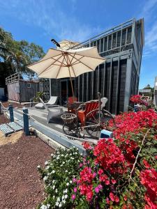 un patio con mesa, sombrilla y flores en Casa Garfio, en Barra de Navidad