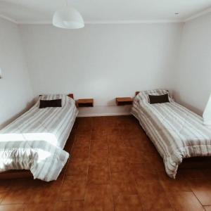 two beds in a room with white walls and wooden floors at Hostel Ohana in Mar del Plata