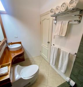 a bathroom with a toilet and a sink and towels at Torre Mar Galapagos Boutique Suites in Puerto Ayora